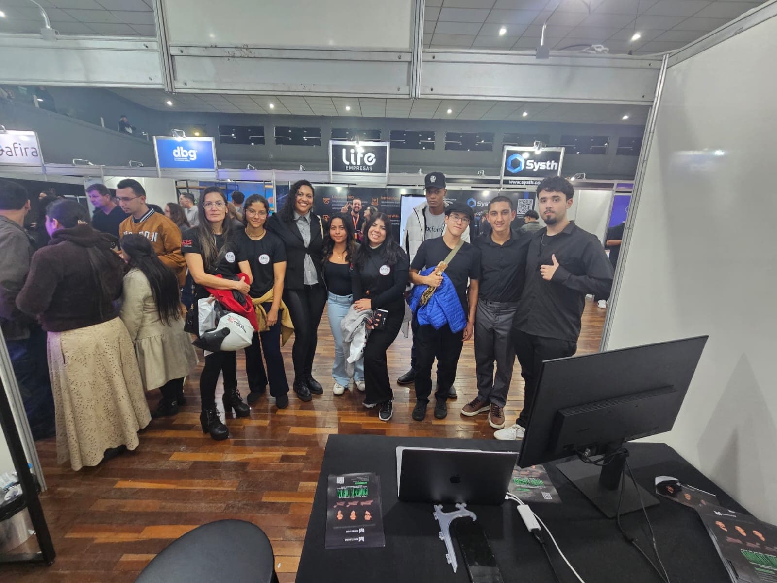 Estande da Mavellium na FITEC 2026 — Rebeca Gonçalves da Silva interagindo com o Janus CMS para análise de dados com GA4 e Clarity